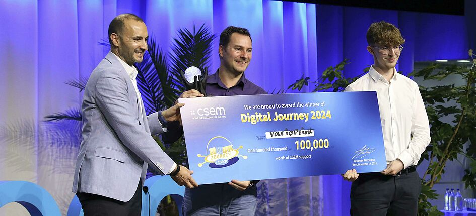 Bahaa Roustom von CSEM (links) überreicht den Hauptpreis des Wettbewerbs CSEM Digital Journey 2024 an das Team der Varioprint AG: Remo Kürsteiner, Leiter IT bei Varioprint (Mitte), und Kevin Willeit, IT-Mitarbeiter bei Varioprint (rechts). Bild: CSEM